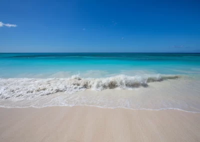Turquoise Caribbean water breaking gently on an empty stretch of white sand