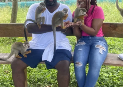 Dos visitantes sentados con monos ardilla